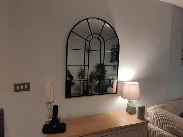 Arched window-style mirror hung above a sideboard