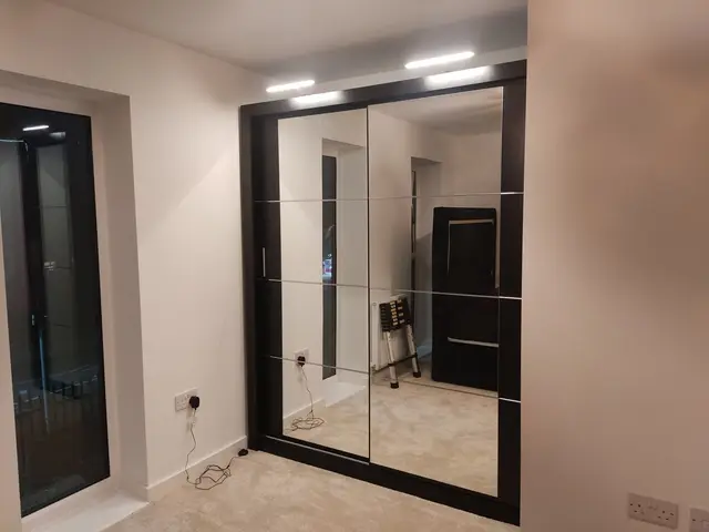Mirrored sliding-door wardrobe assembled in a bedroom