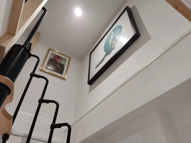 Picture frames hung high on a stairwell wall